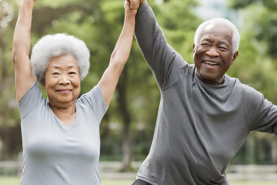 A couple smiling with raised arms outdoor.